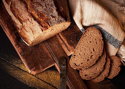 Aufgeschnittene Rhöner Kruste auf einem Holzbrett mit Brotmesser.