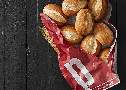 Papperz-Brötchen in einer leicht aufgerissenen roten Pappert-Papiertüte auf dunklem Untergrund.